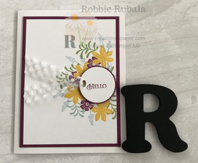 This card uses a technique and fun way to attach your ribbon. Check out the details for this pretty Collage Stamped Hello creation.